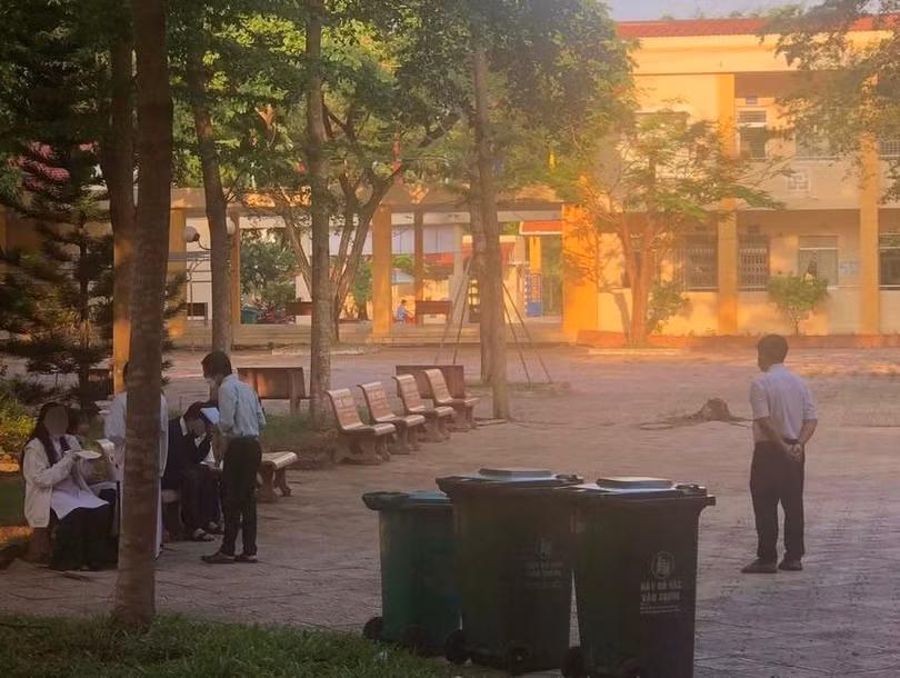 Các học sinh bị thầy phó hiệu trưởng bắt ra ghế đá ở sân trường ngồi ăn thức ăn mà học sinh đã quẳng vào thùng rác. Ảnh Phụ huynh cung cấp 