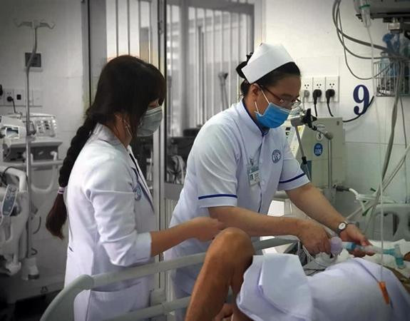 Bác sĩ Võ Ngọc Anh Thơ (bên trái) cùng các đồng nghiệp chăm sóc bệnh nhân tại Khoa Bệnh nhiệt đới, Bệnh viện Chợ Rẫy.