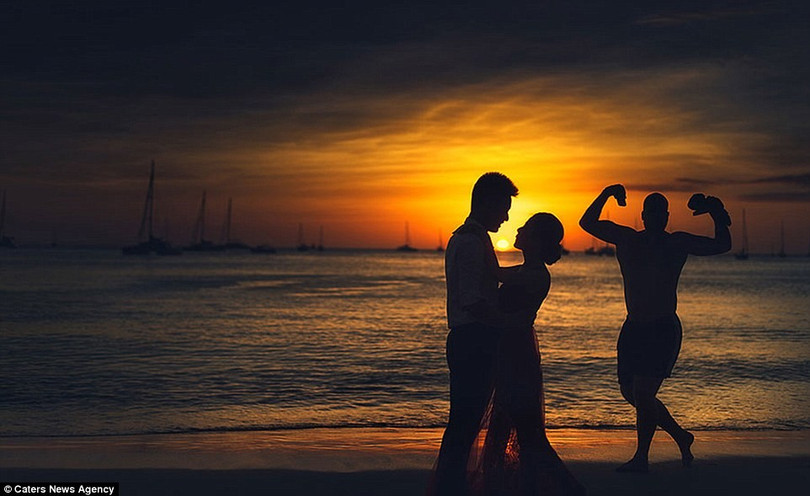 Vào chiều hoàng hôn lãng mạn, biển lặng yên không gợn sóng, cặp uyên ương nhìn nhau say đắm bên cạnh một người đàn ông đang... khoe cơ bắp.
