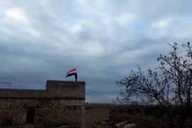 Quân đội Syria thượng cờ trên nóc nhà cao tầng của thành phố Manbij, Aleppo.