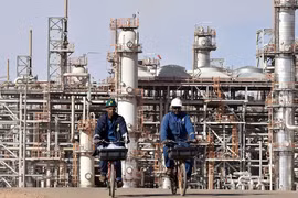 Hai công nhân bên ngoài một cơ sở sản xuất khí đốt ở Algeria (Ảnh: AFP).