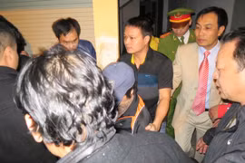 Bà Châu Thị Thu Nga (giữa, chụp mũ) bị bắt giữ và dẫn giải về trại giam vào tối khuya 7-1