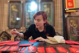 Một nữ thư pháp gia còn rất trẻ đang cho chữ tại phố ông đồ trước Nhà văn hóa Thanh niên 