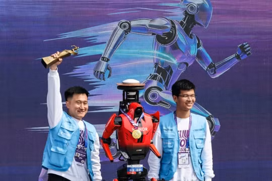 Các thành viên nhóm ăn mừng bên cạnh robot hình người Lightning của Honor. Ảnh: Reuters.