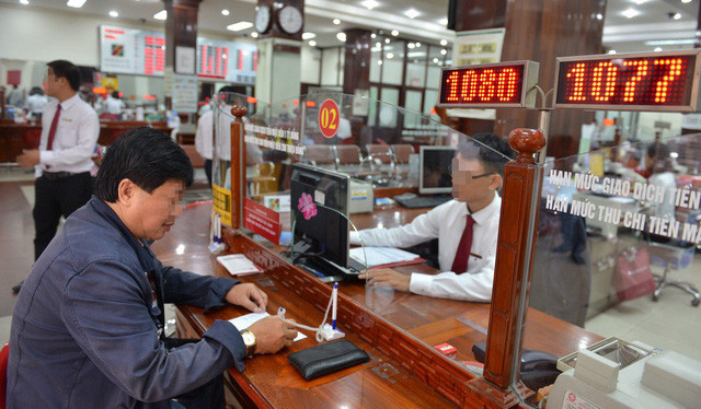 Khách hàng giao dịch tại một ngân hàng ở Q.1, TP.HCM - Ảnh: D.Ph. 