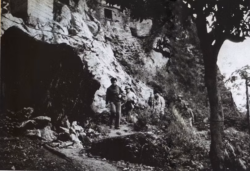 Nhà báo Takano Isao bước ra khỏi một hang động hướng về phía đỗ xe. Nhà báo Takano Isao bước ra khỏi một hang động hướng về phía đỗ xe.