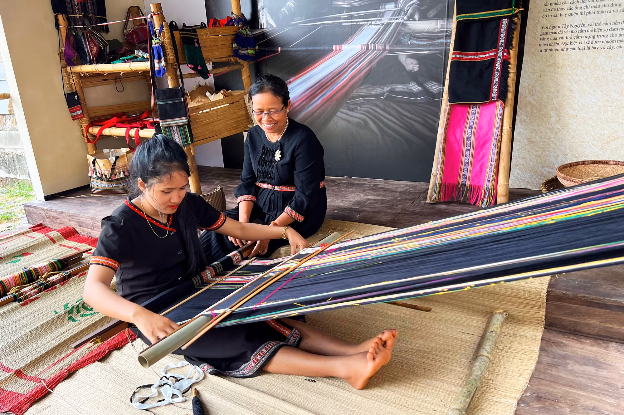 Bà H'Yam BKrông vui vẻ hướng dẫn thiếu nữ dệt thổ cẩm Bà H'Yam BKrông vui vẻ hướng dẫn thiếu nữ dệt thổ cẩm