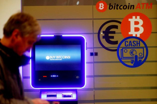 Một người đàn ông đi ngang qua một cây ATM bitcoin ở Vilnius, Litva. Ảnh: CNBC