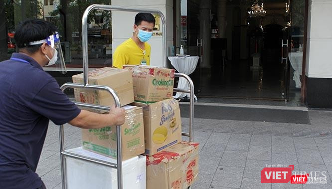 Trần Đức Phong (áo vàng) và Bùi Văn Nghĩa (áo xanh đen), một người là bác sĩ tới từ Hà Nội, một người là doanh nghiệp ở TP.HCM, đang hì hụi đẩy xe quà là tấm lòng của bà con Sài Gòn gửi tới các y, bác sĩ của đoàn Bệnh viện Bạch Mai tăng cường cho thành phố. Ảnh: GVT.