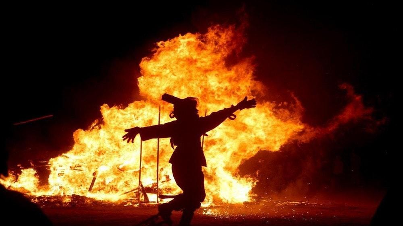 Một người đàn ông nhảy bên một đám cháy lớn trong lễ kỷ niệm lễ hội Lửa Một người đàn ông nhảy bên một đám cháy lớn trong lễ kỷ niệm lễ hội Lửa