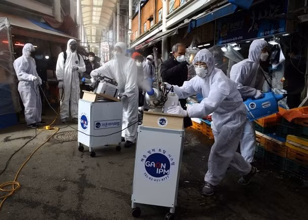 Dịch bệnh COVID-19 lây lan mạnh ở Hàn Quốc, các nhân viên phòng dịch phun thuốc khử trùng trong chợ (Ảnh: Getty).
