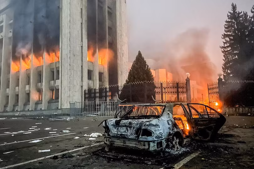 TRụ sở chính quyền và xe cảnh sát bị những người biểu tình đốt phá ở Almaty (Ảnh: AP).