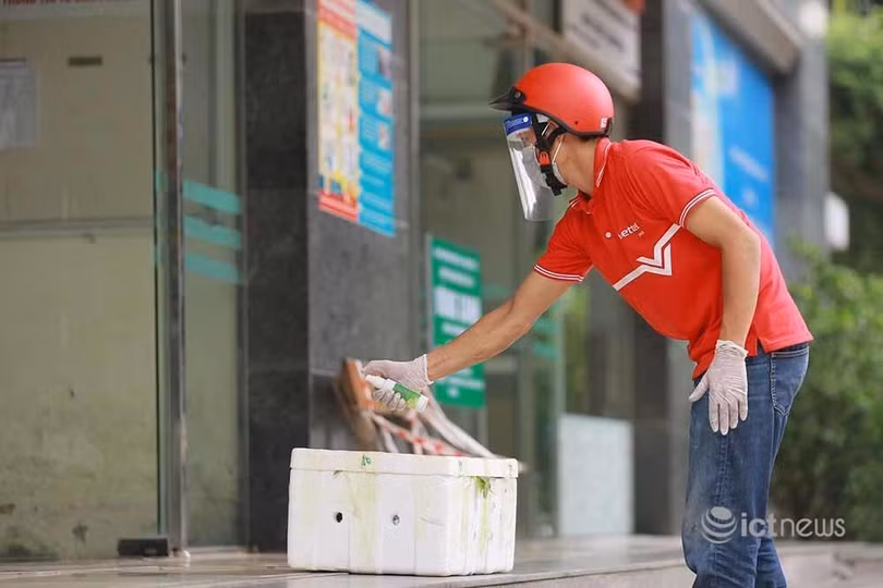 Nhân viên bưu chính xịt khử khuẩn hàng trước khi đặt ở vị trí chung cư "vùng xanh" quy định.
