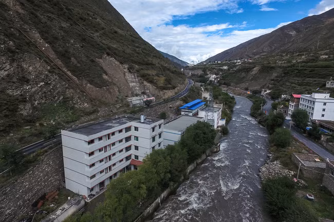 Hình 1: Khu mỏ Bitcoin mà nhiếp ảnh gia đến thăm là ngôi nhà được lợp bằng tôm màu xanh biển đầy cá tính nằm khiêm tốn cạnh một nhà máy điện ở châu tự trị Ngawa, thuộc khu tự trị người Khương ở Tây Tạng, Tứ Xuyên