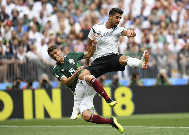 Tiền vệ người Đức Sami Khedira và hậu vệ của Hector Moreno của Mexico ngã sau khi cố gắng đánh đầu.