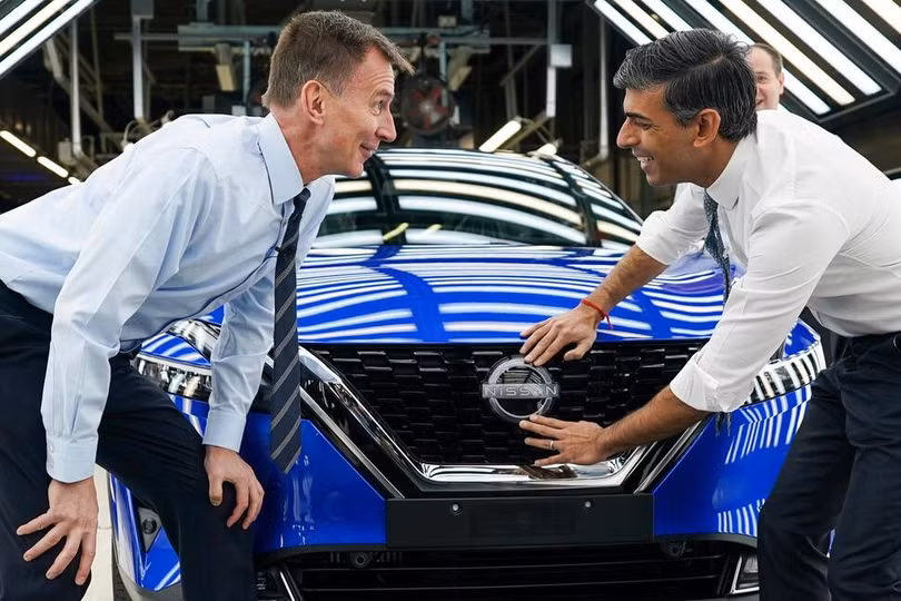 Thủ tướng Anh Rishi Sunak và Bộ trưởng Bộ Tài chính Jeremy Hunt gắn huy hiệu Nissan vào một chiếc ô tô khi đến thăm nhà máy của Nissan ở Sunderland, Anh. Ảnh AP