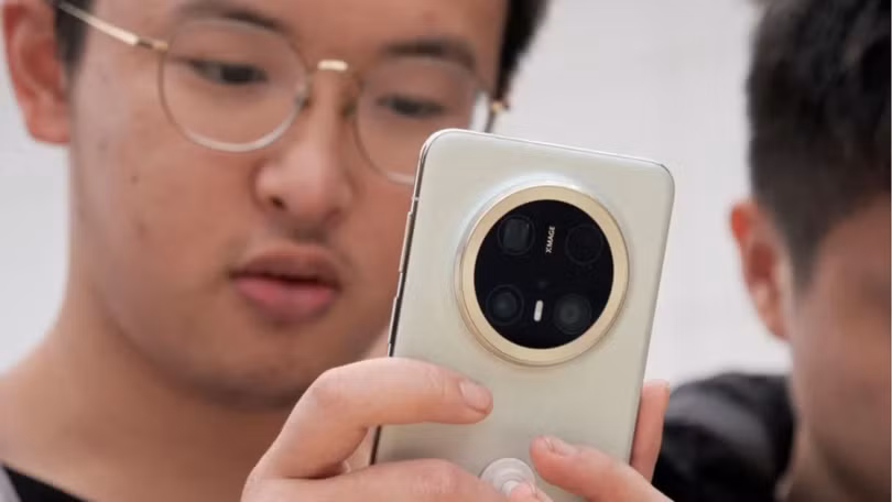 Một du khách đang xem dòng điện thoại thông minh Mate 70 mới nhất của Huawei tại một cửa hàng ở Bắc Kinh. Ảnh: Reuters.