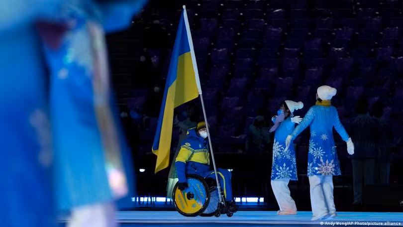 Vận động viên Maxim Warowji cầm cờ của đội Ukraine dẫn đầu đoàn Ukraine tiến vào sân vận động Tổ chim Bắc Kinh (Ảnh: Deutsche Welle). Vận động viên Maxim Warowji cầm cờ của đội Ukraine dẫn đầu đoàn Ukraine tiến vào sân vận động Tổ chim Bắc Kinh (Ảnh: Deutsche Welle).