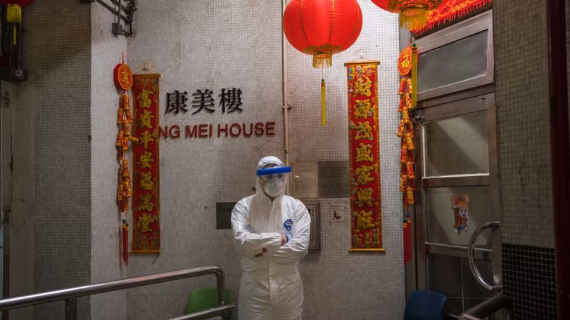 Một nhân viên y tế mặc đồ bảo hộ đứng bảo vệ bên ngoài lối vào tòa nhà chung cư ở Tsing Yi (Hồng Kông) sau khi phát hiện cư dân thứ hai nhiễm virus tại đây. Hơn 100 người sống tại tòa chung cư này đã được sơ tán (ảnh Getty Images)
