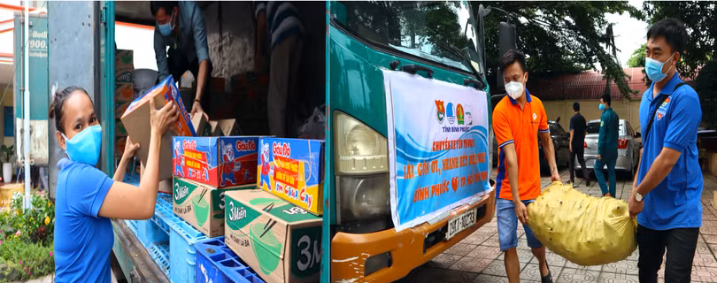 Các bạn trẻ Bình Phước hào hứng khuân vác nông sản và thực phẩm xếp lên xe để trao niềm yêu thương đến thành phố mang tên Bác
