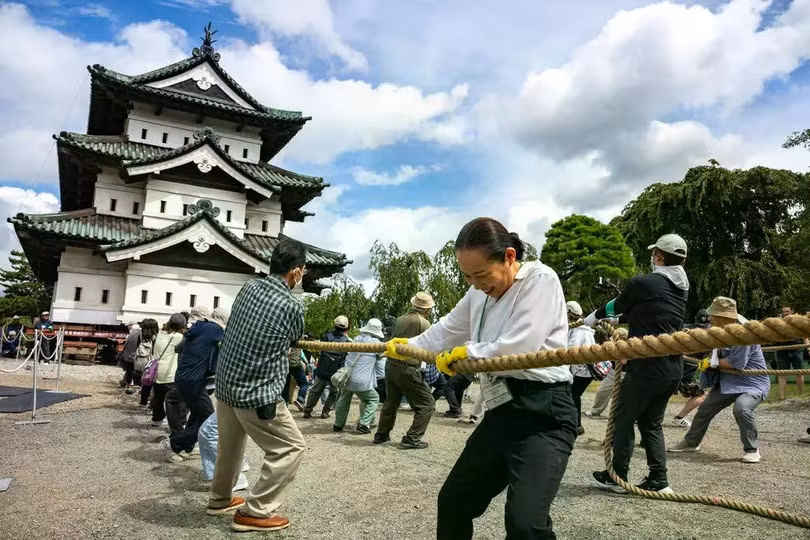 Người lớn và trẻ em dùng tay kéo lâu đài Hirosaki ở tỉnh Aomori, Nhật Bản. Phương pháp cổ xưa này được gọi là hikiya. Ảnh: AFP.