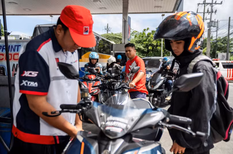 Các tài xế xe máy xếp hàng chờ trong khi một nhân viên đang đổ xăng cho xe máy tại một trạm xăng ở thành phố Quezon, khu vực đô thị Manila, Philippines ngày 9/3. Ảnh: Reuters.