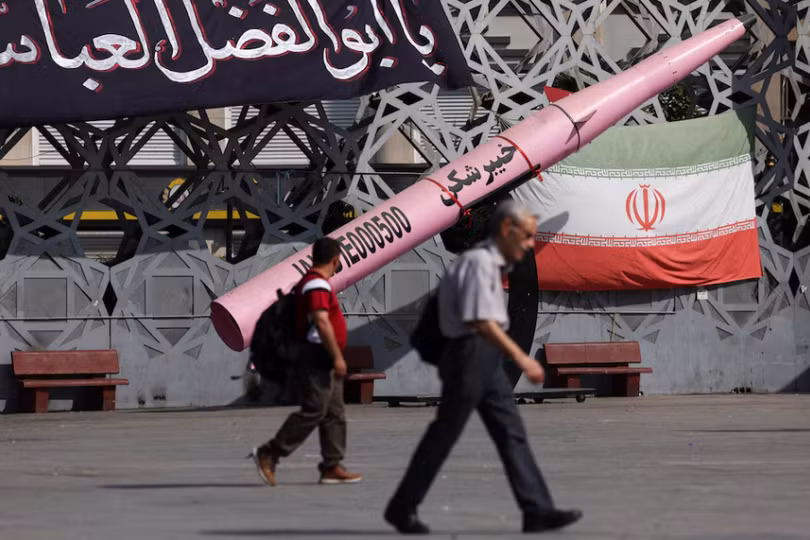 Người dân đi bộ bên cạnh mô hình tượng trưng của một tên lửa Iran và quốc kỳ Iran tại Quảng trường Imam Hussein ở Tehran, Iran, ngày 12/7. Ảnh: Reuters.
