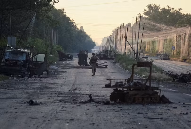 Một binh sĩ thuộc Lữ đoàn hợp nhất "Khyzhak" của Cảnh sát tuần tra Ukraine đi dọc theo một con đường gần lưới chống UAV và các phương tiện quân sự bị phá hủy khi tham gia nhiệm vụ bảo vệ một con đường khỏi UAV của Nga giữa các thị trấn tiền tuyến Druzhkivka và Kostiantynivka, ngày 24/6. Ảnh: Reuters.