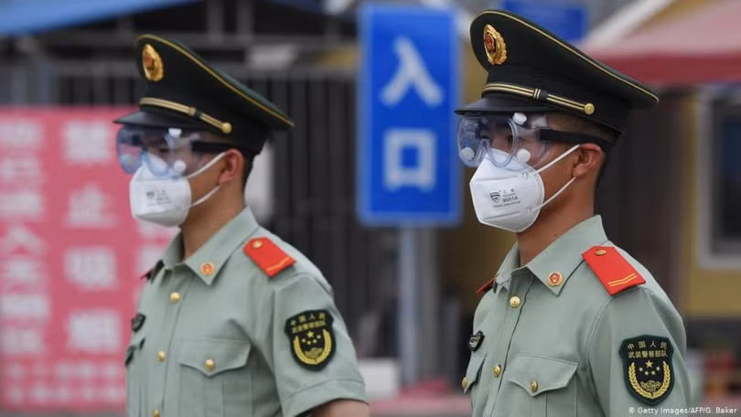 Cảnh sát vũ trang được triển khai bảo vệ khu chợ Tân Phát Địa đã đóng cửa đang được các nhân viên phòng dịch khử trùng (Ảnh: AFP)