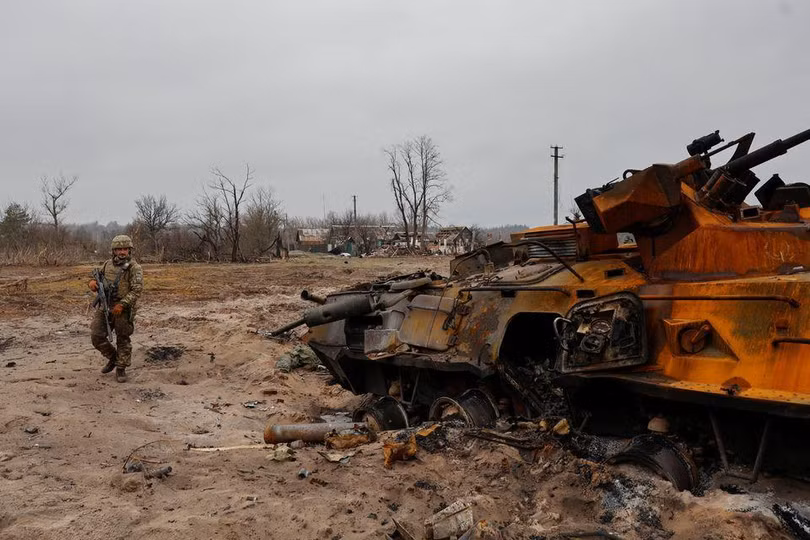 Một binh sĩ Ukraine kiểm tra xác xe thiết giáp của quân đội Nga gần Kiev (Ảnh: Reuters)
