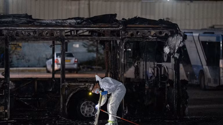 Các nhân viên pháp y Israel kiểm tra một trong ba chiếc xe buýt trống phát nổ ở Bat Yam, ngoại ô phía nam Tel Aviv. Ảnh: Getty.
