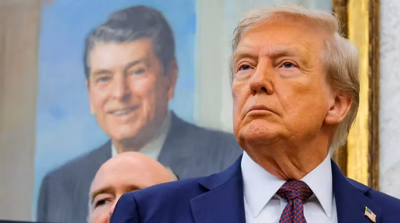 Tổng thống Donald Trump, trước bức tranh của cố Tổng thống Ronald Reagan, tại Phòng Bầu dục ở Nhà Trắng ở Washington, D.C. Ảnh: Reuters.