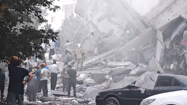 Mọi người nhìn vào thiệt hại của các tòa nhà tại Quảng trường Nobonyad sau cuộc không kích của Israel vào ngày 13/6 tại Tehran, Iran. Ảnh: Getty.