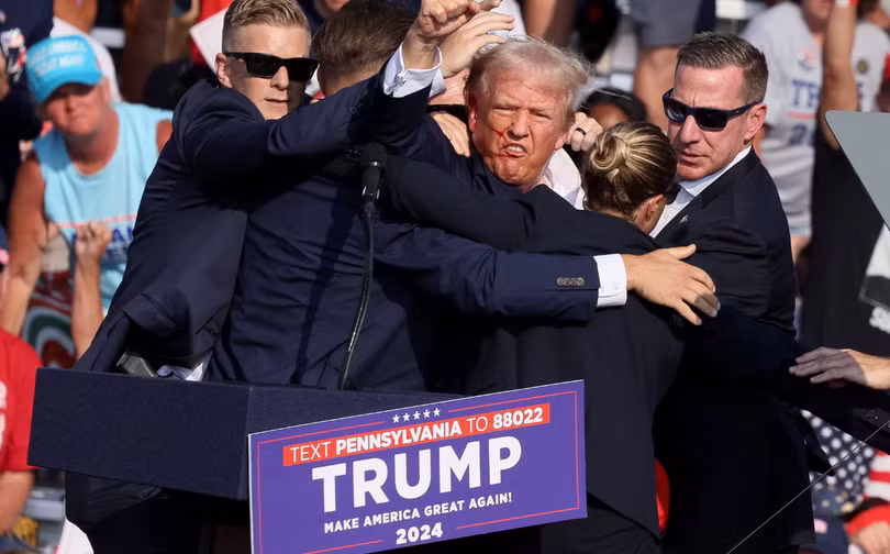 Ông Donald Trump ra hiệu với khuôn mặt đầy máu sau khi bị bắn vào tai phải trong một cuộc vận động tranh cử ở Butler, Pennsylvania, Mỹ ngày 13/7/2024. Ảnh: Reuters.