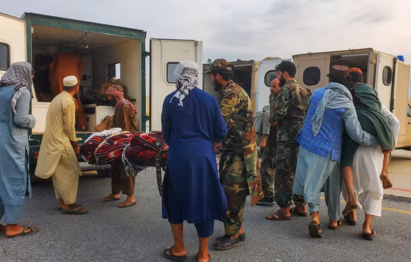 Binh lính Taliban và thường dân đưa nạn nhân động đất lên xe cứu thương tại sân bay ở Jalalabad, Afghanistan ngày 1/9. Ảnh: Reuters.