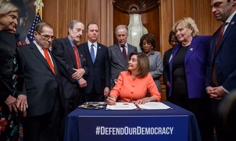 Chủ tịch Hạ viện Nancy Pelosi ký 2 điều khoản luận tội Trump để chuyển cho Thượng viện (Ảnh: Guardian)
