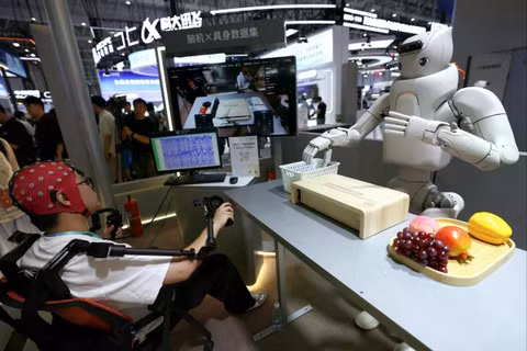 Một kỹ sư đội mũ giao diện não-máy tính để điều khiển robot hình người tại gian hàng của Fourier Intelligence trong Hội nghị Robot Thế giới tháng trước ở Bắc Kinh. Ảnh: Reuters.