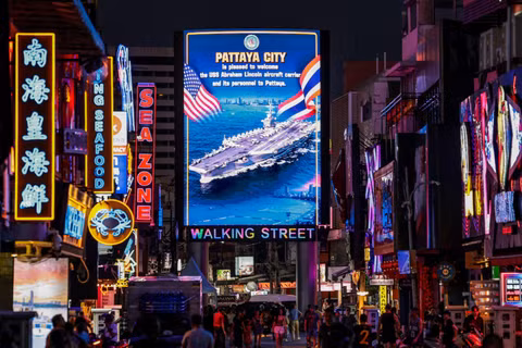 Người dân đi ngang qua màn hình LED chào đón các quân nhân Mỹ từ tàu sân bay lớp Nimitz USS Abraham Lincoln, đang neo đậu tại cảng Laem Chabang để nghỉ ngơi sau một chuyến triển khai dài ngày ở Trung Đông, tại thành phố Pattaya, Thái Lan, ngày 3/9. Ảnh: Reuters.