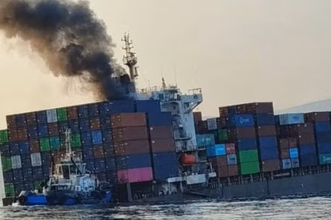 Khói bốc lên từ con tàu container GFS Pride đang nghiêng sau khi nó va phải thủy lôi ở eo biển Hormuz vào ngày 14/10. Ảnh: RT.