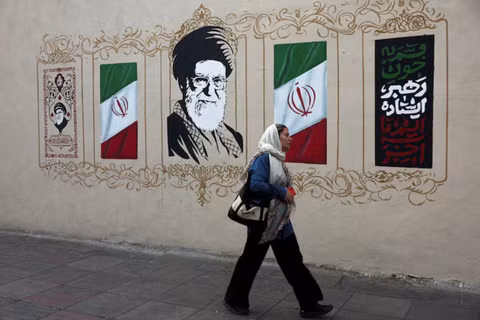 Một người phụ nữ đi ngang qua bức tranh tường mô tả cố lãnh đạo tối cao của Iran, Ayatollah Ali Khamenei, trên một con phố ở Tehran, Iran, ngày 13/8. Ảnh: Reuters.