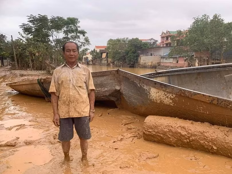 Ông Bình bên chiếc đò bị gãy đôi sau khi va đập mạnh trong lũ dữ (ảnh: Dương Phong)