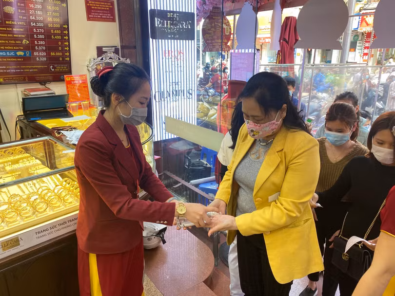 Khách hàng được đo nhiệt độ và sát khuẩn tay trước khi vào cửa hàng Khách hàng được đo nhiệt độ và sát khuẩn tay trước khi vào cửa hàng