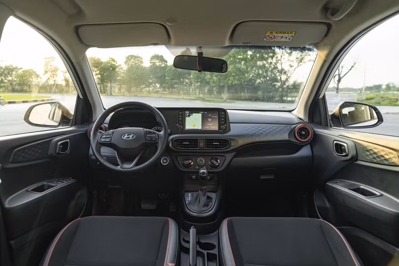Nội thất New Grand i10 nổi bật với ghế bọc da màu tối kết hợp đường viền đỏ.