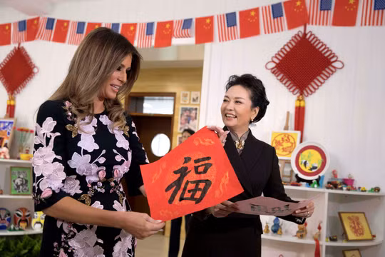 Đệ nhất phu nhân Mỹ Melania Trump và đệ nhất phu nhân Trung Quốc Bành Lệ Viện cùng giơ cao bức thư pháp chữ Hán có nghĩa "vận may" do các em học sinh viết trong chuyến thăm trường tiểu học Banchang ở Bắc Kinh vào tháng 11/2017. Ảnh: Reuters.