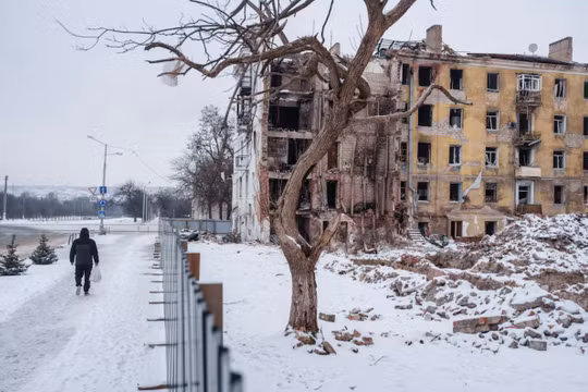 Một cư dân đi bộ bên cạnh một tòa nhà chung cư bị hư hại ở Kramatorsk, thuộc vùng Donetsk, Ukraine ngày 22/1. Ảnh: Reuters.
