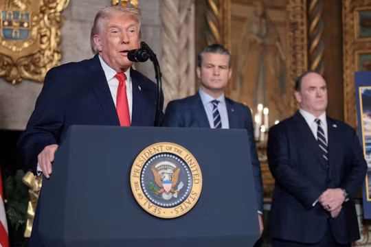 Tổng thống Mỹ Donald Trump đưa ra thông báo về "Hạm đội Vàng" của Hải quân, trong khi Bộ trưởng Quốc phòng Pete Hegseth và Bộ trưởng Hải quân John Phelan lắng nghe, tại Mar-a-lago ở Palm Beach, Florida, Mỹ, ngày 22/12. Ảnh: Reuters.