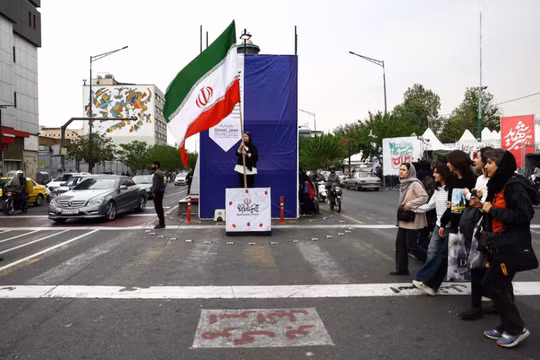 Một người phụ nữ cầm cờ Iran trên đường phố, trong bối cảnh lệnh ngừng bắn giữa Mỹ và Iran, tại Tehran, Iran ngày 20/4. Ảnh: Reuters.