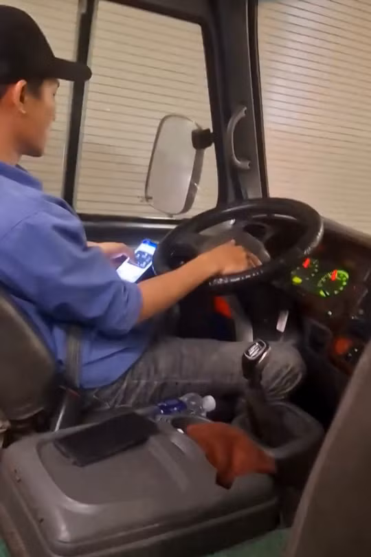 Tài xế vừa lái xe vừa lướt điện thoại. Ảnh cắt từ clip.