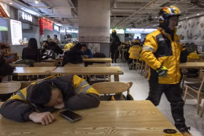 Một nhân viên giao hàng ở Trung Quốc tranh thủ nghỉ ngơi sau giờ cao điểm ăn trưa. Ảnh: WSJ.