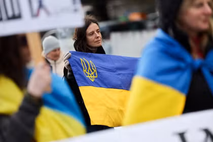 Một người phụ nữ cầm cờ Ukraine tại một cuộc biểu tình gần văn phòng Liên Hợp Quốc, vào ngày diễn ra cuộc đàm phán hòa bình do Mỹ làm trung gian giữa Nga và Ukraine tại Geneva, Thụy Sĩ ngày 17/2. Ảnh: Reuters.